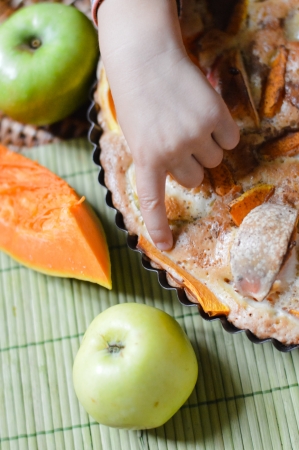 Child hand over apple and pumpkin pie closeup tastingの写真素材