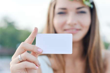 Young beautiful woman holding blank business card with copy spaceの写真素材