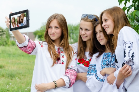 Four teen girls taking picture of themselves using tablet computerの写真素材