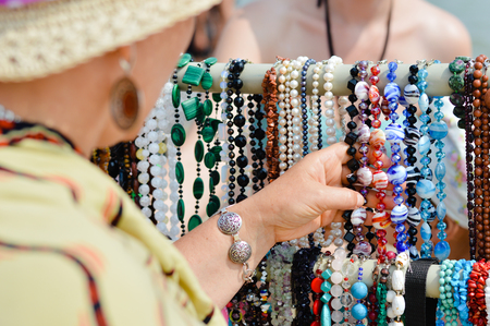 Woman choosing jewelry in row of necklaces and braceletsの写真素材