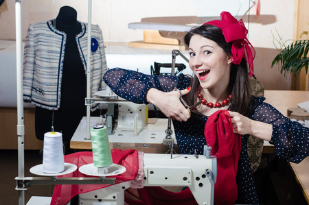 Funny young pinup woman with sewing machine and scissorsの写真素材