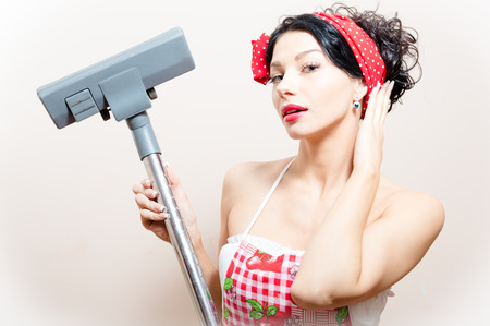 closeup portrait on funny charming young beautiful brunette woman pin-up girl with vacuum cleaner raised in hand straightens her hairの写真素材