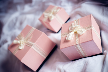 Three gorgeous beautiful luxury boxes pink presents with white ribbon on white bed backgroundの写真素材