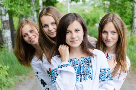 standing together in forest or park team of 4 blond & brunette girlfriends young beautiful women having fun posing happy smile & looking at camera on summer green outdoors background portrait imageの写真素材