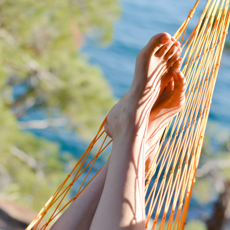 closeup of feet in a hammock on the beautiful summer sea backgroundの写真素材
