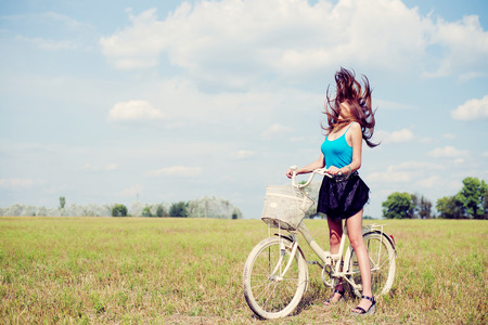 joyful freedom: sexy young pretty lady cycling in fields under bright blue summer sky on green copy space background, portraitの写真素材