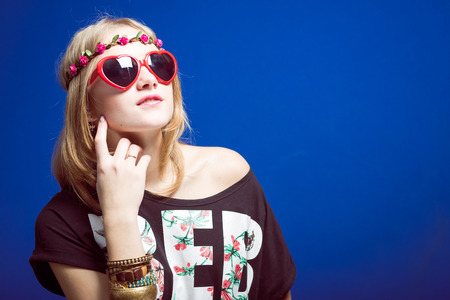 Studio portrait of teenage hipster or hippie girl wearing trendy flower wreath over blue copy space backgroundの写真素材