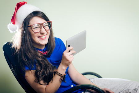 Girl in Christmas hat and sunglasses holding a tabletの写真素材