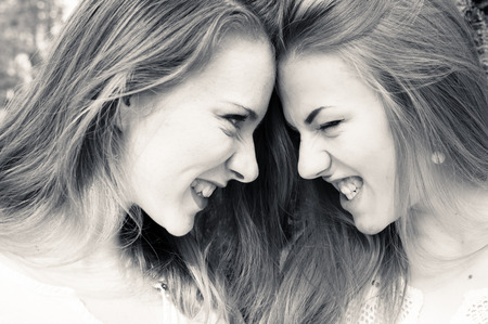Closeup picture of two beautiful young ladies looking and roaring at each otherの写真素材