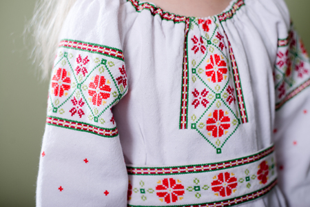 Close up of pretty girl wearing Ukrainian handmade embroidered clothes with floral ornament