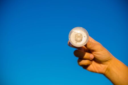 LED lamp in hand against bright blue sky copyspace backgroundの写真素材