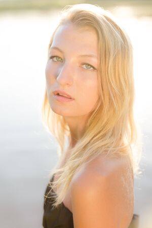 Close up picture of amazing calm beautiful blond young female with green eyes on water backgroundの写真素材
