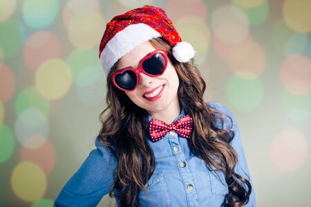 Funny hipster girl in heart shape sunglasses wearing xmas santa hat over olive copy space backgroundの写真素材