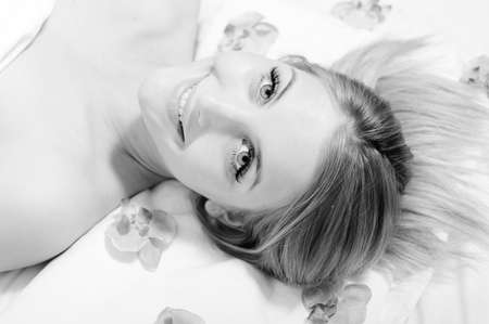 closeup black and white picture of funny sexy blue eyes girl beautiful blond young woman having treatment procedures happy smiling, looking at camera on white background portraitの写真素材