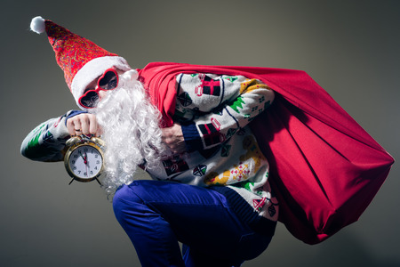 Picture of funny Santa Claus with alarm clock wearing heart shape sunglasses on bright festive bokeh backgroundの写真素材