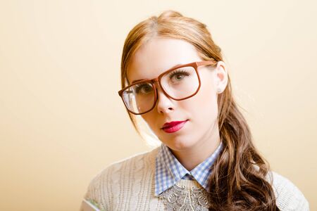 Close-up portrait of beautiful lady in glasses. Freelancer lady with long brown hair posing for photographer isolated on cream background.の写真素材