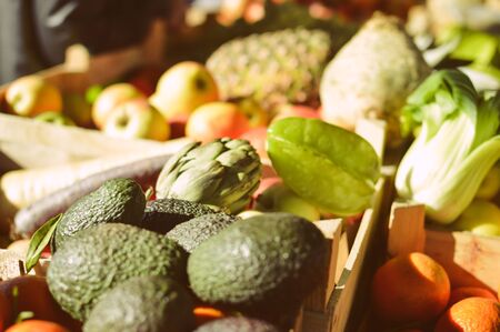 Closeup picture of artichoke, avocado and other fruits in piles on a market stall backgroundの写真素材