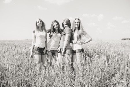 Four happy smiling beautiful young women friends having fun on summer day outdoors backgroundの写真素材