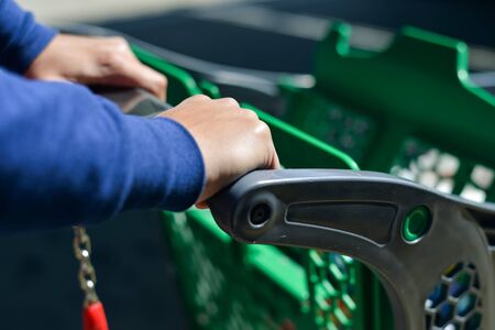 Closeup picture of male hand holding shopping push cart on car parkingの写真素材