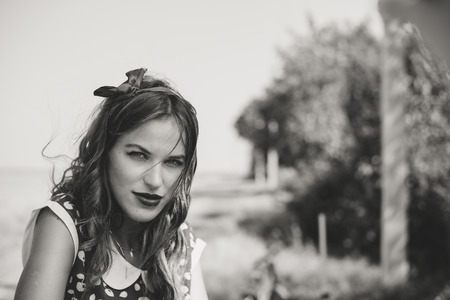 Black and white image of young beautiful brunette pinup woman sexy lady on countryside summer background copy space portraitの写真素材