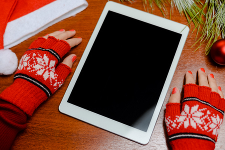 Woman's hand with red wool glove with tablet pc on wood background ready for Christmasの写真素材