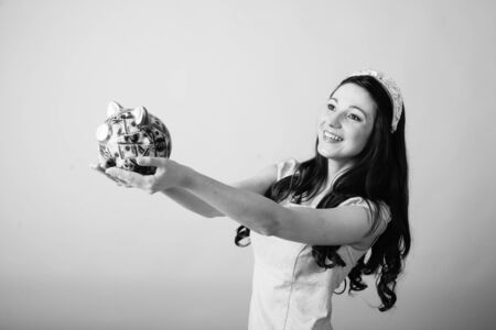 Black and white image of beautiful young woman holding US banknotes and piggy bankの写真素材