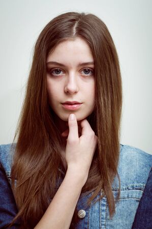 portrait of the beautiful young girl with long brown hair wearing jeans jacket nude makeup in studioの写真素材
