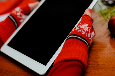 Female Santa Claus holding mobile tablet pc in hands, mockup screen festive Christmas background. Closeup view photoの写真素材