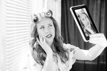 Black and white picture of beautiful young pinup woman happy smiling taking selfie or selfy photo...