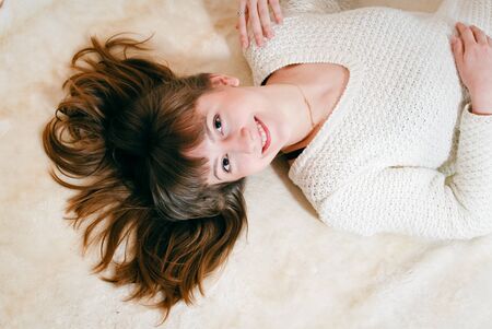 Young beautiful woman in white warm knitted handmade clothes at home. Model fashion shooting. Autumn, winter season.の写真素材