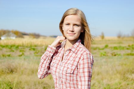 Close up portrait of attractive blond young woman standing outdoors on countryside landscape backgroundの写真素材
