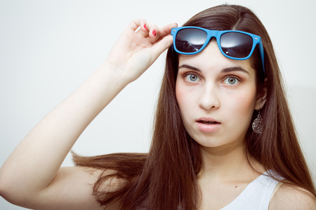 Surprised young attractive caucasian stylish woman wearing sunglasses on studio background. Closeup portrait, trendy lifestyleの写真素材