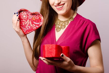 Joyful attractive positive woman holding gift box on light background. Closeup portrait of excited cheerful pretty ladyの写真素材