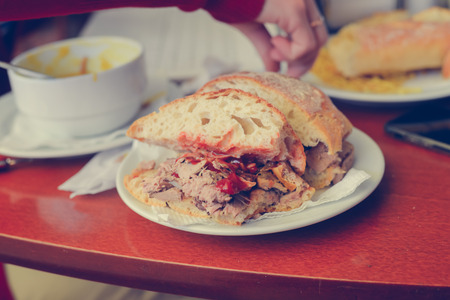 Closeup of female eating and working on laptop computer, wooden table background. Modern meeting busy communication lifestyle conceptの写真素材