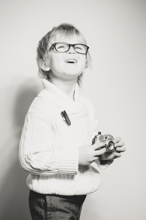 Portrait of young child holding photography camera on light background. Close up picture of equipment study and play activityの写真素材