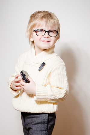 Portrait of young child holding photography camera on light background. Close up picture of equipment study and play activityの写真素材