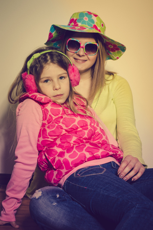 Happy cheerful attractive family wearing winter clothing and bright summer hat ready for season travel fun lifestyle. Close up portrait of joyful hugging people with healthy smile on light backgroundの写真素材
