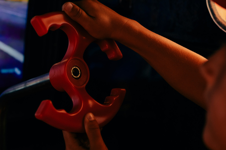 Close up on kid hands playing behind the wheel of a game console background. Electronic business entertainment activity. Playful education simulation technologyの写真素材