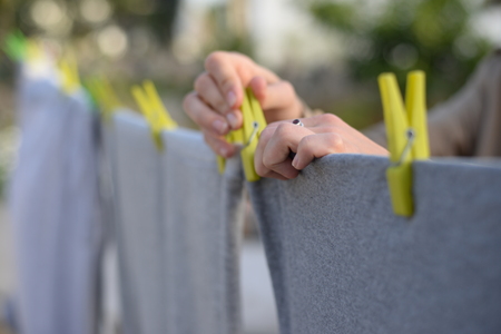 Clothes hanging on sunny light outdoors landscape background, close up photography on woman hand.の写真素材