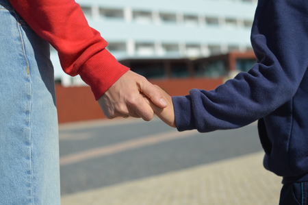 Close up on hand of mother and child on sunny outdoors background. Happy assistance, healthy motion togetherness. Human love, relation, protection and support. Holding emotional connection.の写真素材