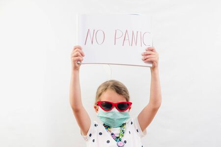 Little blond girl wearing disposable mask and sunglasses holding no panic sign over white backgroundの写真素材