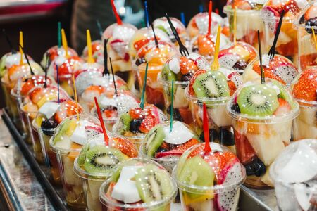 Fruit Salad arranged in plastic cups on a market stall with small fork inside, takeaway healthy snackの写真素材