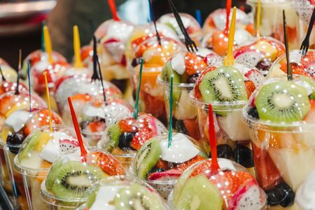 Fruit Salad arranged in plastic cups on a market stall with small fork inside, takeaway healthy snackの写真素材