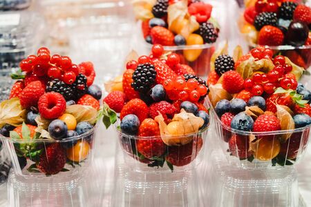 Fruit Salad arranged in plastic cups on a market stall with small fork inside, takeaway healthy snackの写真素材