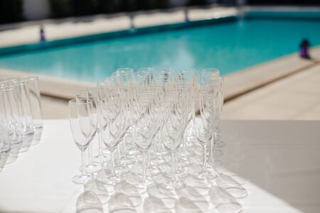 Champagne glasses prepared for cocktail party on table by the swimming poolの写真素材