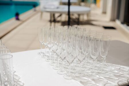 Champagne glasses prepared for cocktail party on table by the swimming poolの写真素材