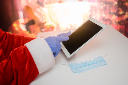 Santa Claus in a medical mask with a tablet. Online greetings, ordering services for Christmas and...