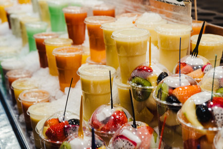 Fruit Salad arranged in plastic cups on a market stall with small fork inside, takeaway snackの写真素材