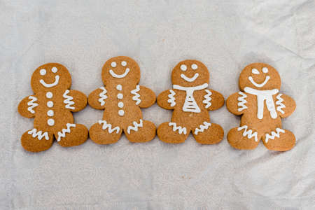 Smiling gingerbread man with sugar, spices, and vintage rolling pin on rustic, textile linen...
