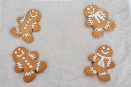 Smiling gingerbread man with sugar, spices, and vintage rolling pin on rustic, textile linen background. Top view still life with natural light.の写真素材